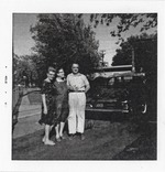 One man and two women posing for photograph in front of a car